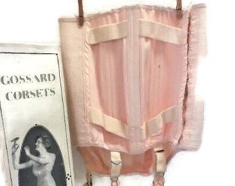 May include: A pink Gossard corset with white straps and a lace trim. The corset has a front closure and is designed to be worn with stockings.