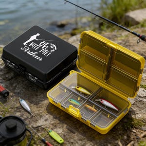 May include: Black and yellow fishing tackle boxes with various fishing lures. The black box has a white graphic of a fisherman and the text "Oh Bite Me! Arthur". The yellow box is open, revealing several compartments with colorful lures.