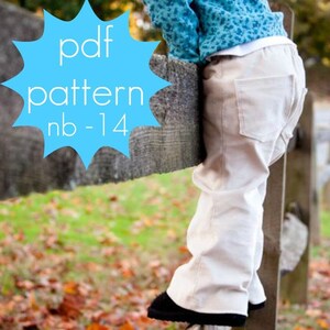 Può includere: Un bambino con pantaloni beige e scarpe nere è appoggiato a una staccionata di legno. Il bambino indossa anche un top blu fantasia. Una grafica blu a forma di stella con il testo "pdf pattern nb-14" si trova nell'angolo in alto a sinistra.