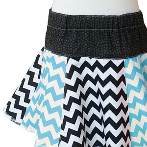 May include: A black, white, and blue chevron patterned skirt with a black waistband. The waistband has a small white polka dot pattern.