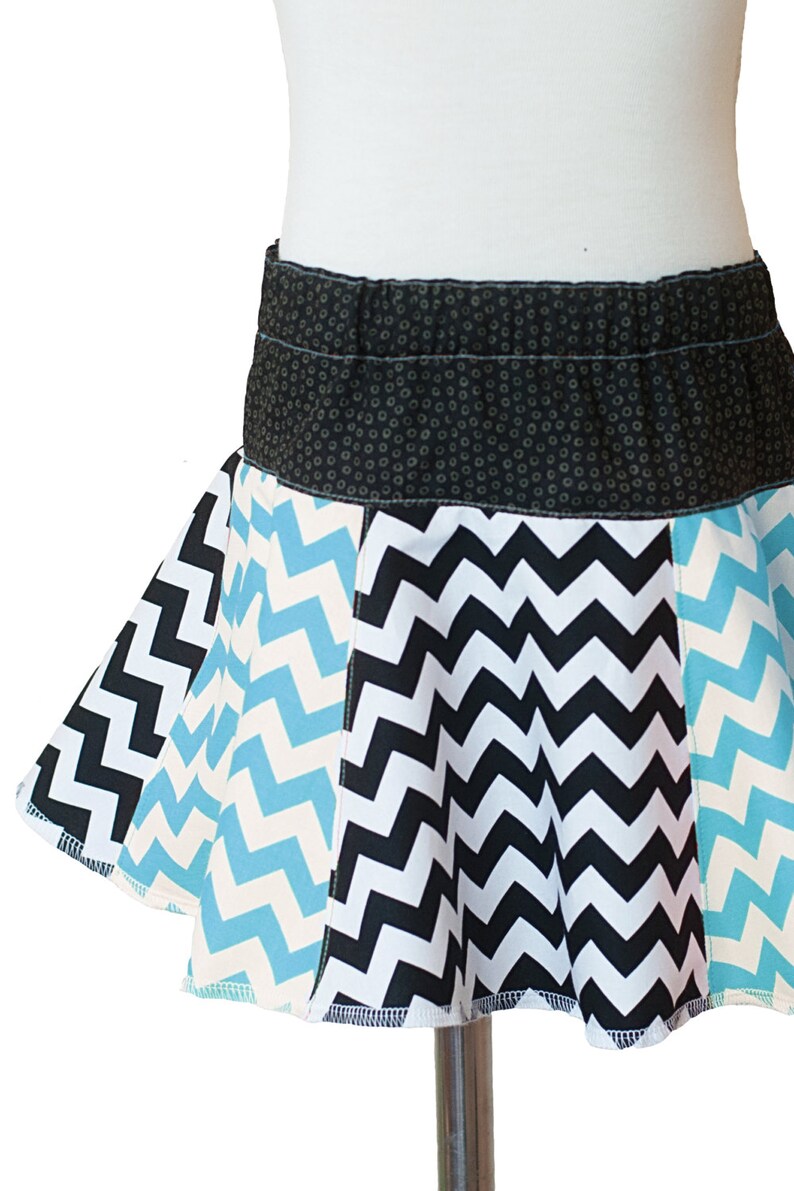 May include: A black, white, and blue chevron patterned skirt with a black waistband. The waistband has a small white polka dot pattern.