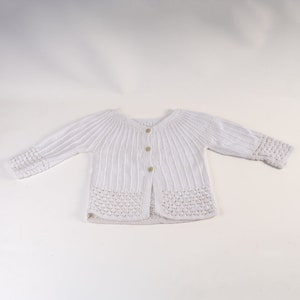 Könnte beinhalten: Weißer Strickcardigan mit Knopfleiste und Häkelrand.