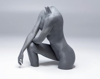 May include: A gray sculpture of a human torso and arms in a seated pose. The figure is headless, with the arms crossed and the legs bent. The sculpture is made of a smooth material and is set against a white background.