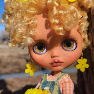 Spring Blythe-pop: goudgekruld haar, bloemenaccessoires, zachte pastellook
