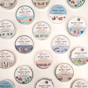 May include: A collection of washi tape rolls with various designs, including apples, bumblebees, suns and moons, snails, raccoons, moths, frogs, nature designs, and strawberries. Each roll is labeled with the text "WASHI TAPE" and the brand name "Lucid Moon Studio". The tape widths vary from 15mm to 25mm.