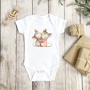 May include: White baby onesie with a graphic of two mice hugging. The mice are gray and brown with pink accents.