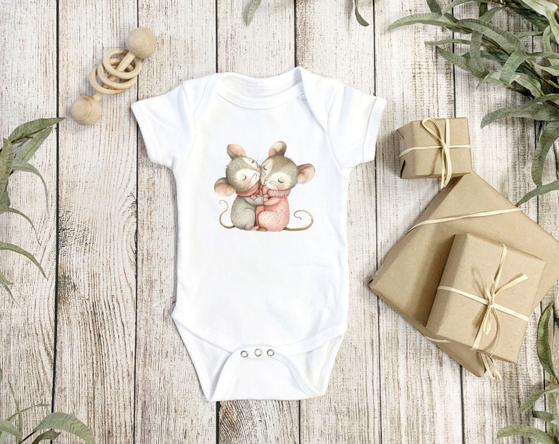 May include: White baby onesie with a graphic of two mice hugging. The mice are gray and brown with pink accents.