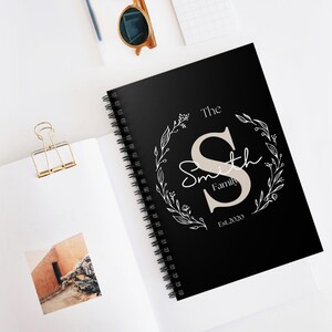 Puede incluir: Cuaderno espiral negro con un diseño floral blanco y el texto "The Smith Family Est. 2020".