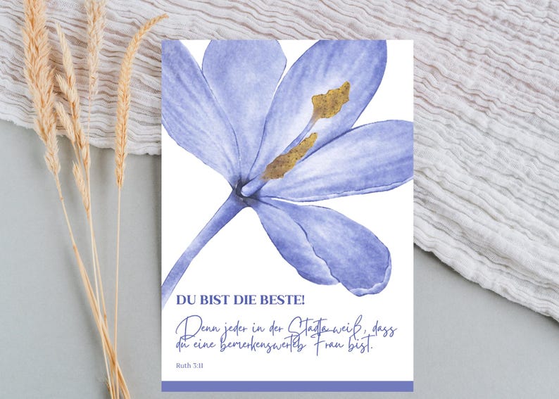 May include: A watercolor print featuring a large, light purple flower with a golden center. The print includes German text that reads "DU BIST DIE BESTE!" and a quote from Ruth 3:11. The background is white.