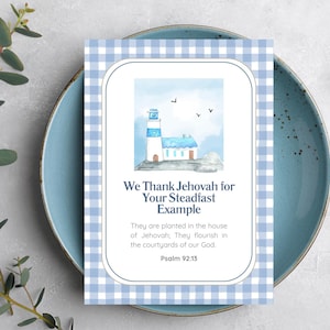 May include: A greeting card featuring a watercolour illustration of a lighthouse and a small house, set against a blue sky. The card has a blue and white gingham border and the text: "We Thank Jehovah for Your Steadfast Example."