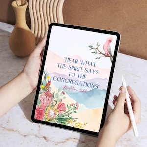 Peut inclure: Une tablette numérique affiche un design à l'aquarelle avec le texte "Hear What The Spirit Says To The Congregations" et "Revelation 3:22". Le design comprend un oiseau rose sur une branche et des éléments floraux.