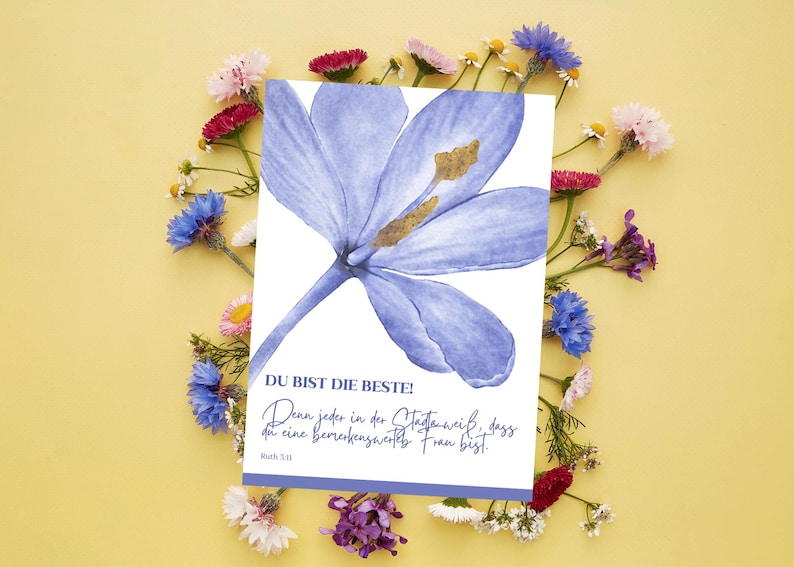 May include: A greeting card with a watercolor illustration of a blue flower with a gold center. The card has German text that reads "DU BIST DIE BESTE!" surrounded by colorful flowers on a yellow background.
