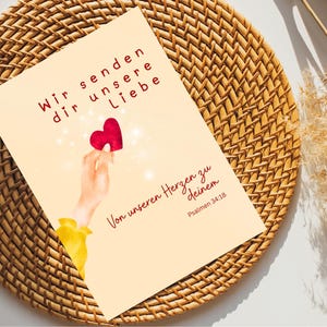 Peut inclure: Carte de vœux avec texte allemand, « Wir senden dir unsere Liebe » (Nous vous envoyons notre amour), représentant une main tenant un cœur rouge. La carte contient du texte allemand supplémentaire, « Von unseren Herzen zu deinem » et un verset biblique.