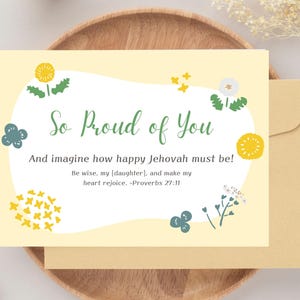 Può includere: Un biglietto di auguri con la scritta "So Proud of You" in verde. Il biglietto ha uno sfondo giallo con illustrazioni floreali. È inclusa una busta. È presente anche il testo "And imagine how happy Jehovah must be!"