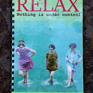 May include: A spiral-bound notebook with a green cover featuring the word "RELAX" in red, with the text "Nothing is under control" below. The cover also includes a vintage image of three women wading in water.