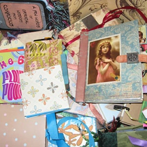 Peut inclure: Une collection de petits journaux faits à la main avec divers motifs et designs. Les journaux sont faits de papier et de tissu et présentent différentes couleurs, notamment le bleu, le vert, le rose et le brun. Certains journaux portent des titres, tels que "The 6" et "A Few Notes of Oriental Wisdom".