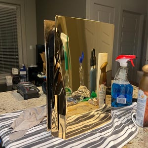 May include: A gold-colored metal console with a black trim. The console is sitting on a striped towel on a countertop.