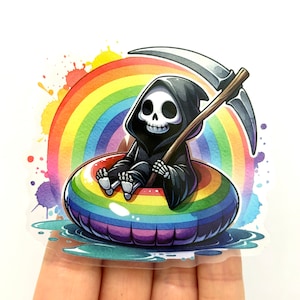 Op de afbeelding: Een cartoon-skelet met een zwarte kapucijnerjurk drijft in een regenboogkleurige opblaasring. Het skelet houdt een zeis vast en glimlacht. De achtergrond is een aquarelregenboog met kleurspatten.