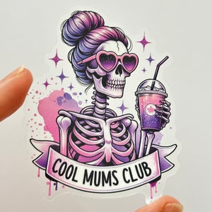 May include: A sticker featuring a pink and purple skeleton wearing heart-shaped sunglasses and holding a purple drink with a straw. The sticker has a banner that says "Cool Mums Club".
