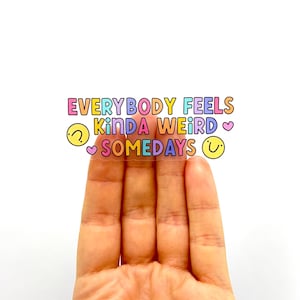 May include: A clear sticker with the text "EVERYBODY FEELS kinda WEIRD SOMEDAYS" in rainbow colors with a heart and smiley face on either side.