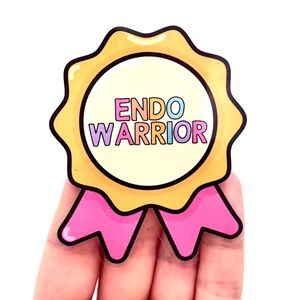 May include: A sticker with the text "ENDO WARRIOR" in a circular design. It has a yellow scalloped border, a light pink ribbon, and a white background. The text is in various colors. A badge of honor.