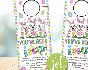 Peut inclure: Une porte-étiquette imprimable avec un fond rayé rose, bleu et jaune. Trois lapins de dessin animé tiennent des œufs de Pâques. Le texte dit "You've Been Egged!" et "There are 20 Easter Eggs hidden in your yard! Hunting then and enjoy! Now it's your turn to spread the CHEER! Egg a friend's house near you!"