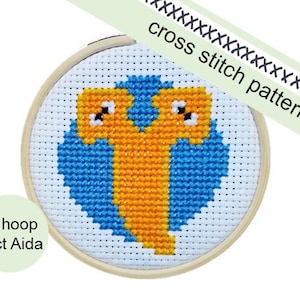 May include: A 3-inch hoop with 11 count Aida fabric, featuring a cross stitch pattern of a blue and orange bird. The pattern is in a wooden hoop.