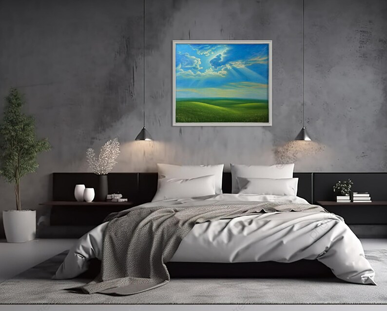 May include: A framed landscape painting depicting a green field under a blue sky with clouds and sun rays. The artwork hangs above a bed with white bedding and a gray blanket. The room has a modern design with gray walls.