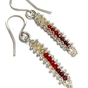 May include: A pair of dangle earrings with a silver chain design. The earrings feature a gradient of small, colorful beads, transitioning from yellow to red and deep red. The earrings have silver hooks.
