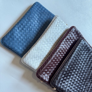Pode incluir: Quatro bolsas retangulares com zíper dispostas em uma fileira diagonal. Cada bolsa apresenta um padrão de grade trançada. As cores de cima para baixo são azul, branco, bordô escuro e marrom escuro, com zíperes correspondentes.