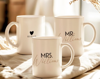 Könnte beinhalten: Drei weiße Keramikbecher mit schwarzer Beschriftung. Die Becher sagen "EST 9.2.23", "MR. Williams" und "MRS. Williams".