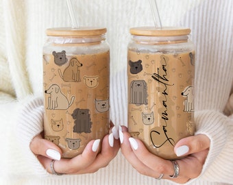 May include: Two clear glass tumblers with bamboo lids and straws. The tumblers are decorated with a pattern of dogs, bones, and paw prints. One tumbler has the name "Samantha" written on it.