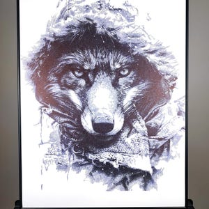 May include: A black and white illustration of a wolf's face, with a detailed, textured design. The wolf is looking directly at the viewer, with a serious expression. The background is white.