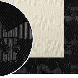 May include: Close-up of a black and white patterned floor mat. The mat has a textured surface and a geometric design.