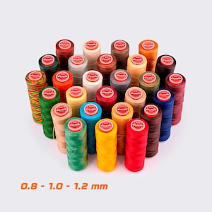 May include: A collection of colorful thread spools in various shades, including red, yellow, green, and blue. The spools are arranged closely together, with the text "0.8 - 1.0 - 1.2 mm" in orange at the bottom. These threads are likely for crafting or sewing.