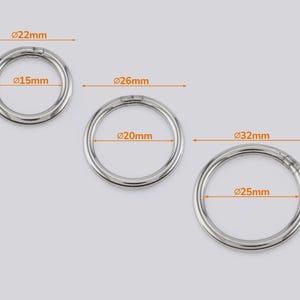 May include: Three silver-coloured metal spring rings with visible measurements. The smallest ring has a 15mm inner and 22mm outer diameter, the middle ring has a 20mm inner and 26mm outer diameter, and the largest ring has a 25mm inner and 32mm outer diameter.