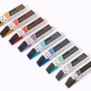 Op de afbeelding: Een assortiment schuursponzen, elk verpakt in een witte doos met kleurgecodeerde labels. De dozen zijn diagonaal gerangschikt, waarbij het productassortiment en de tekst "SANDING SPONGE" worden getoond.