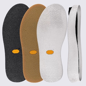 May include: Three flat shoe soles in black, tan, and white, each featuring a textured surface and a small yellow Vibram logo embedded in the center. A fourth white sole is shown from a side profile view, revealing a thick, curved heel structure.