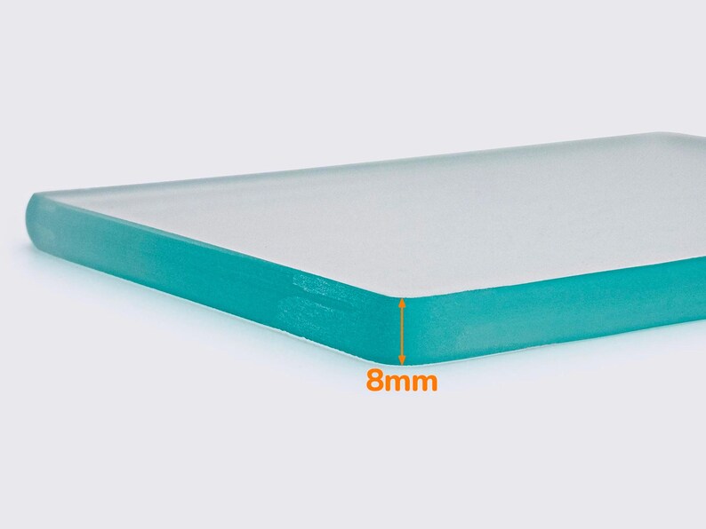 May include: A close-up of a rectangular, clear glass panel with rounded edges. The panel is 8mm thick and has a teal-colored edge. The glass appears to be smooth and reflective.