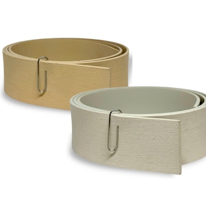 May include: Two rolls of textured paper, one beige and one off-white, are shown. Each roll is held together with a silver paper clip. The paper has a slightly rough surface, and the rolls are on a white background.