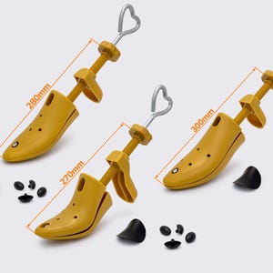 May include: Three yellow shoe stretchers with silver handles and black heel inserts. The shoe stretchers are 270mm, 280mm, and 300mm long. The shoe stretchers have a heart-shaped handle.