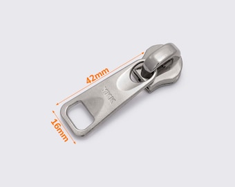 Puede incluir: Tirador de cremallera plateado con logotipo YKK, que mide 42 mm de largo y 16 mm de ancho.