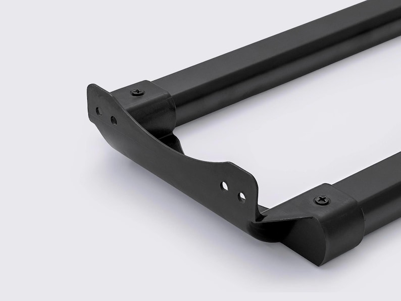 May include: Close-up of a black metal frame with rounded corners and screw details. The frame has a matte finish and appears to be part of a larger structure or piece of furniture. The design is minimalist and modern.