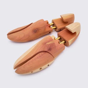 May include: A pair of cedar shoe trees with brass inserts. The shoe trees are designed to help maintain the shape of shoes and absorb moisture.