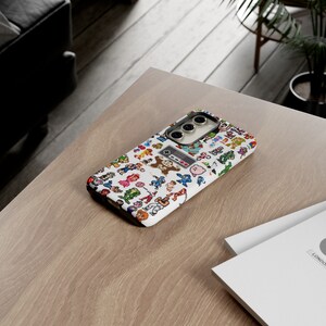 May include: A white phone case with a pixelated design of video game characters. The case has a black camera lens and a black outline around the design.