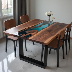 May include: A square dining table with a live edge walnut top and a turquoise epoxy river running through the center. The table has a black metal base and is surrounded by four chairs.