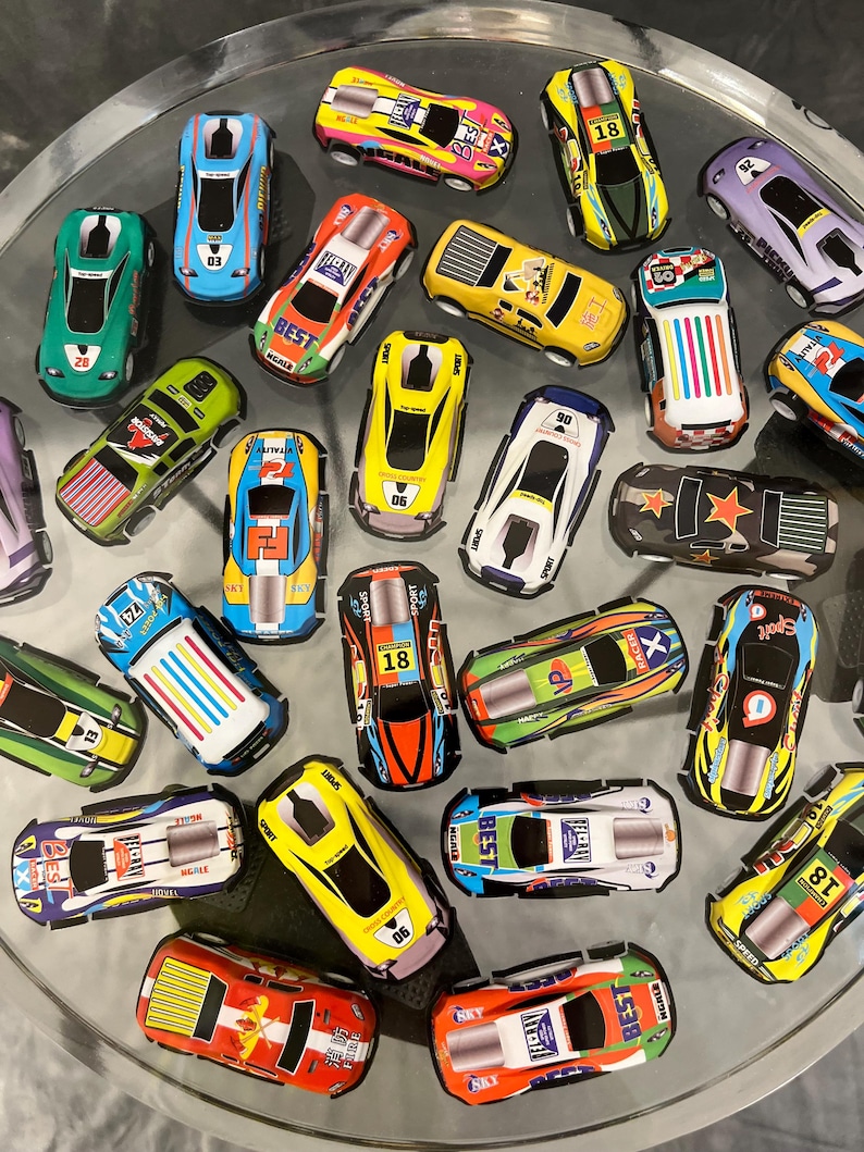 May include: A collection of colorful toy race cars with various numbers and designs. The cars are made of metal and have a pull-back and go action.