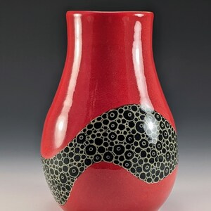 Tall red vase with black and white circle carving