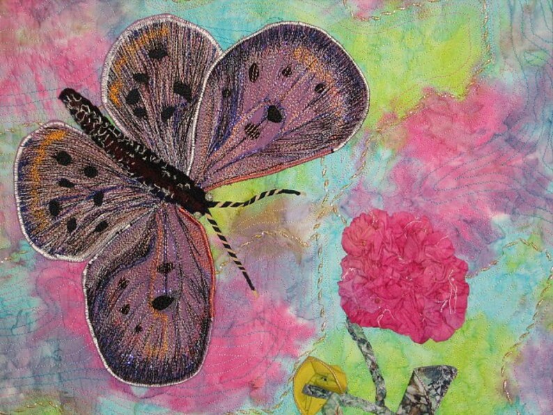May include: A purple and brown butterfly with black spots and a white outline is embroidered on a pink, blue, and green fabric background. A pink flower is in the lower right corner of the image.