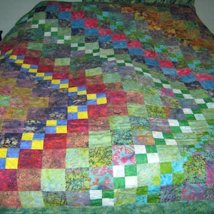 May include: A patchwork quilt with a variety of colors and patterns, including green, blue, yellow, and red. The quilt is made up of squares of different fabrics, and the squares are arranged in a random pattern.